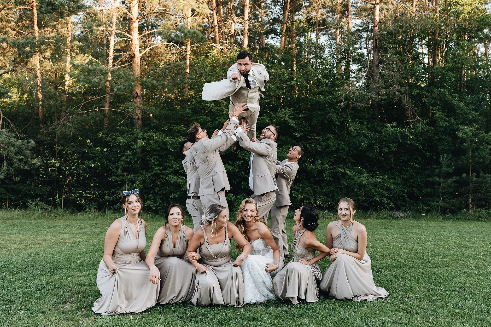 zdjecie mlodego pana w powietrzu podrzucanego przez druzby w zielonym otoczeniu hotelu na opolszczynsie Bajka resort fotografia slubna slaskie